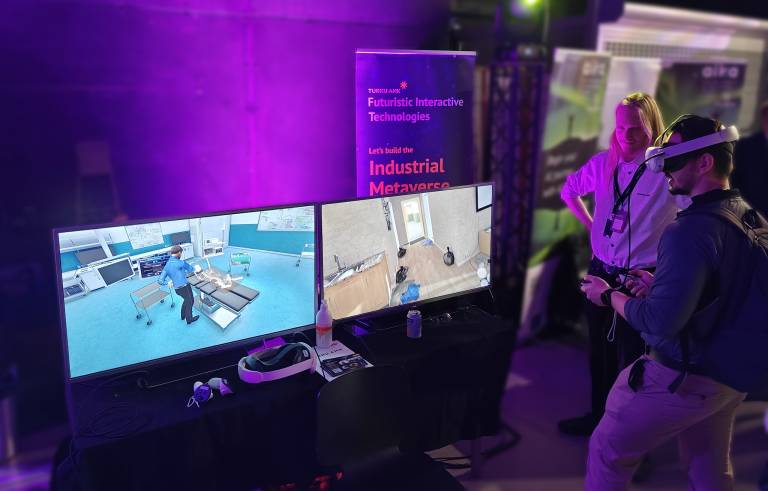 A MatchXR 2025 -attendee trying out the demos of TurkuAMK FIT-group, with the MEDALLION project's MRI-demo video visible on a computer display.